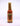 A 5 fl oz bottle of Hell's Kitchen Ginger Devil hot sauce, made with 7 pot primo and fatalli peppers, finished with a gold cap and a yellow label featuring red and gold flame graphics.