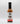 A bottle of Smokin' Ed's Hoisin - Mild with a black cap and white label featuring red flames, a logo, and bold lettering—a great choice for those who enjoy a flavorful but milder hoisin chili pepper sauce.