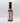 A bottle of Smokin' Ed's Hoisin - Mild with a black cap, seen from the back. The label displays nutrition facts, ingredients, and a flame graphic at the bottom. The mild hot sauce is shown against a plain white background.