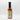 A bottle of Smokin' Ed's Pineapple Teriyaki - Mild with a black cap is shown from the back. Its label features nutrition facts in black text on white. The bottle contains red chile pepper sauce and sits against a plain white background.