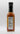 A clear glass bottle of Smokin' Ed's Sazon - Pepper X Hot Sauce with a black cap is shown. The label features nutrition facts and ingredients, and the vibrant orange-red sauce stands out against the white background.