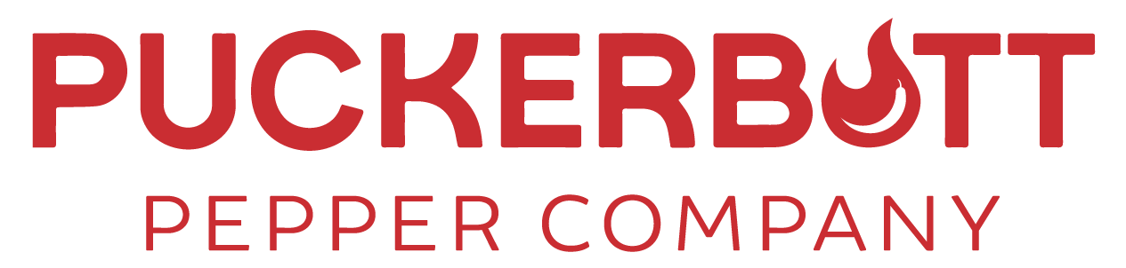 Red logo for PuckerButt Pepper Company with a flame design incorporated into the letter O in BUTT. The text is in bold, uppercase letters on a light background.