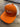 The Orange/White PuckerButt Snapback Hat features the embroidered PuckerButt Pepper Company logo with a red and green chili and "PURE. ORGANIC." text, displayed on a wooden surface.