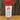 A clear spice jar with a red lid labeled White Wolf Rubs Pack Seasoning sits on a wooden surface against a tree trunk background. This sweet rub is perfect for chicken, pork, ribs, or popcorn.
