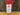 A clear spice jar with a red lid labeled White Wolf Rubs Pack Seasoning sits on a wooden surface against a tree trunk background. This sweet rub is perfect for chicken, pork, ribs, or popcorn.