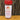 White Wolf Rubs Red Wolf Cajun Seasoning, with a red lid, sits on wood in front of a tree trunk. The label suggests using this spicy rub for gumbo or grilling.